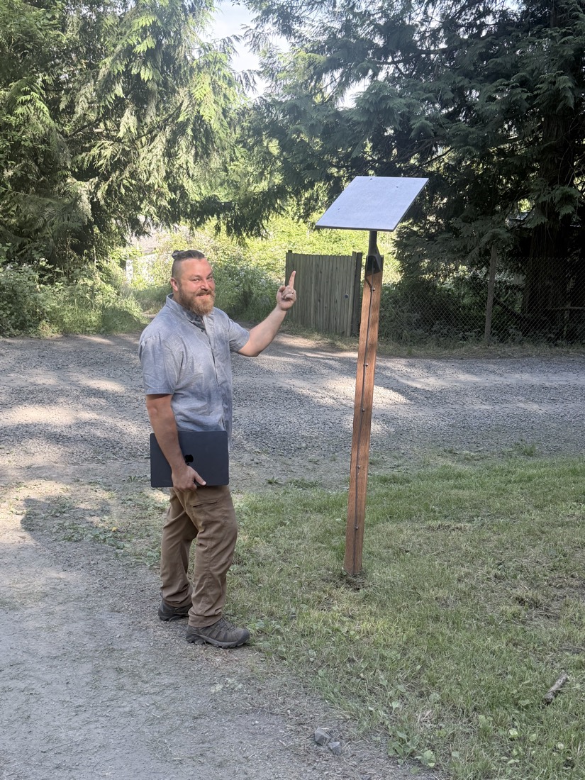 Albert LaScola of Rural Tech and Support standing by the shop sign in Chimacum, WA